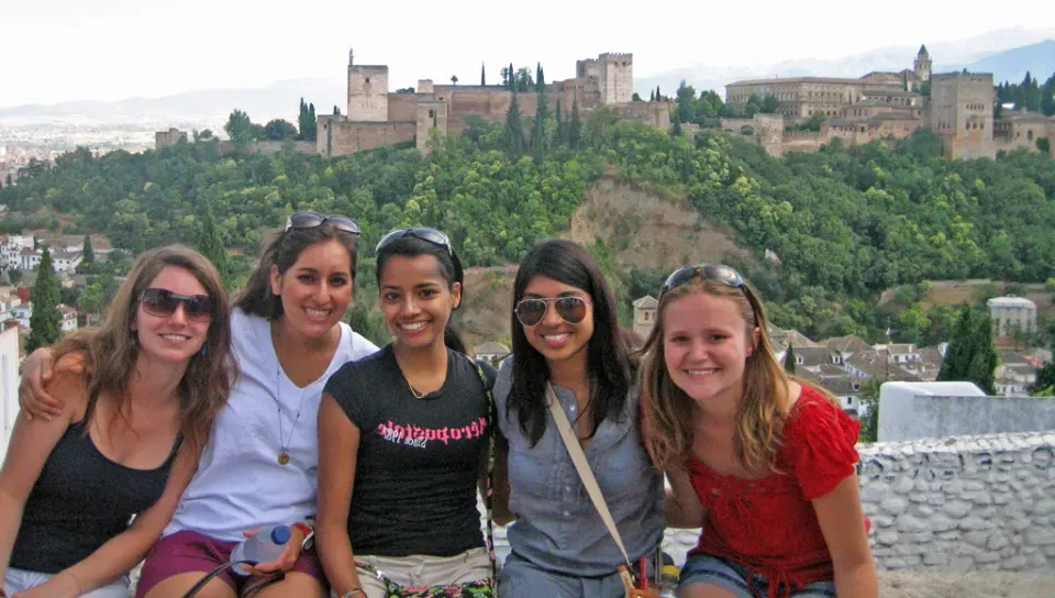 Five U N E students take a photo in front of an old Spanish fortress and palace